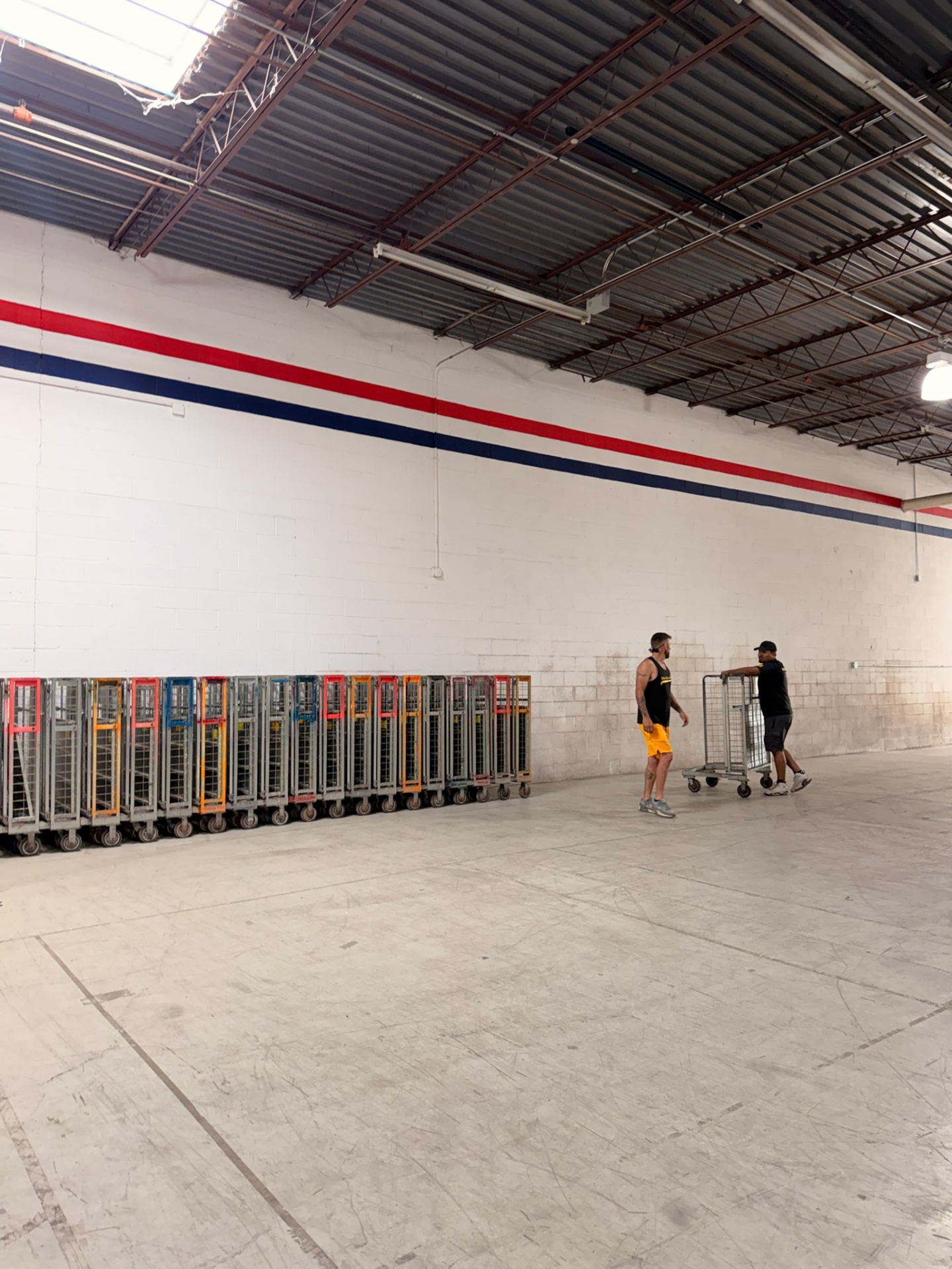 Two movers reviewing equipment carts at a warehouse staging area